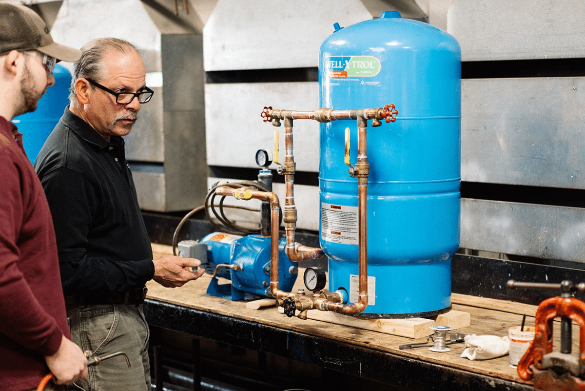 Man working on plumbing with male student